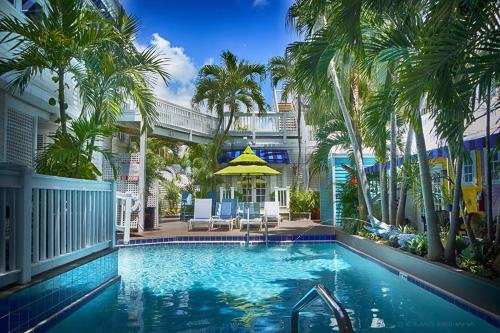 une piscine bordée de palmiers et un bâtiment dans l'établissement La Te Da - Adult Only, 21 or older, à Key West