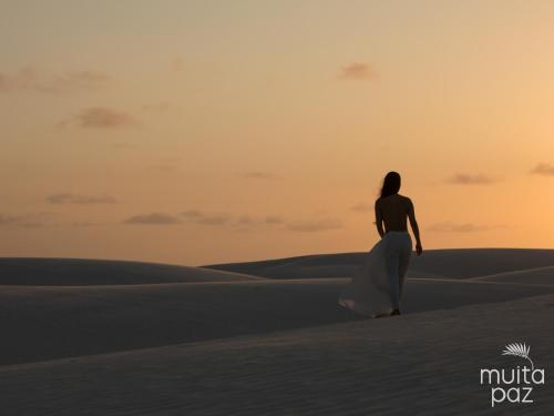 a woman walking in the desert at sunset at Muita Paz in Atins