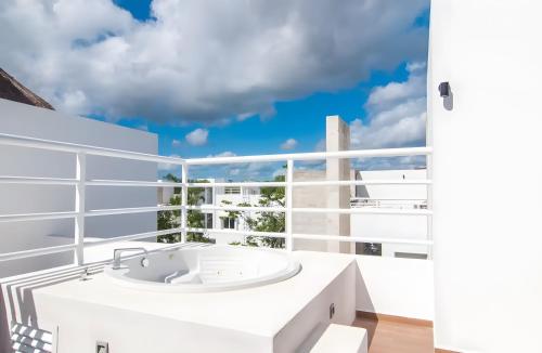 La salle de bains est pourvue d'une baignoire blanche et d'une fenêtre. dans l'établissement Luxury penthouse w-jacuzzi in the heart of Tulum, à Tulum