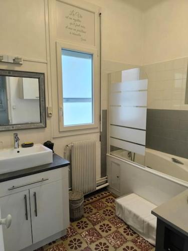 une salle de bain blanche avec un lavabo et un miroir dans l'établissement Appartement charmant et lumineux, à Perpignan