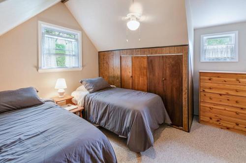 a bedroom with two beds and a dresser and two windows at Lakefront with Lots of Light and Private Dock Access in Ferndale