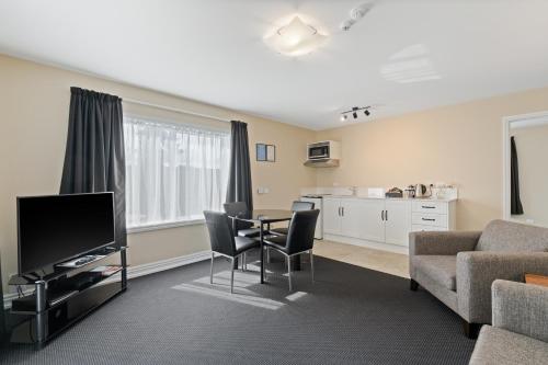 a living room with a table and chairs and a kitchen at Newina Rotorua in Rotorua