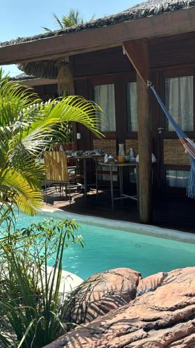 a resort with a pool and a table and chairs at Alma Charme Atins in Atins