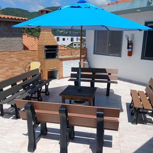 a blue umbrella sitting on a patio with benches at Pousada Souza in Florianópolis