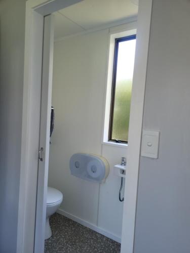 a bathroom with a toilet and a window at Dickson Holiday Park in Thames
