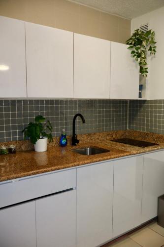 a kitchen with white cabinets and a sink at Isla Verde Modern Apartment with Pool in San Juan