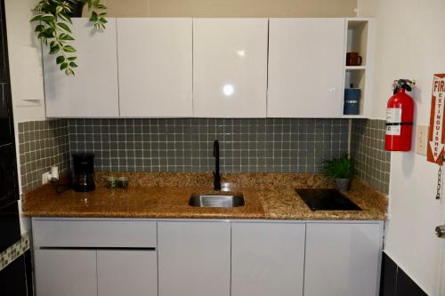 a kitchen counter with a sink and white cabinets at Isla Verde Modern Apartment with Pool in San Juan