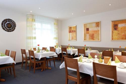 un comedor con mesas blancas y sillas de madera en Hotel Gerberhof, en Backnang