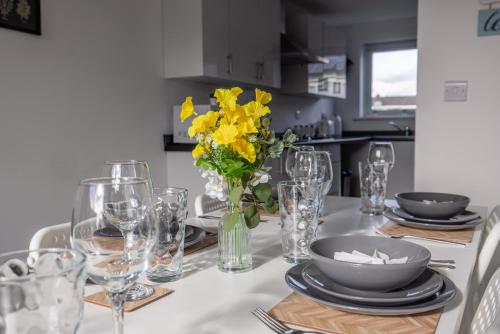 a dining room table with yellow flowers in a vase at Modern 3 Bed House-Free Parking in Cramlington
