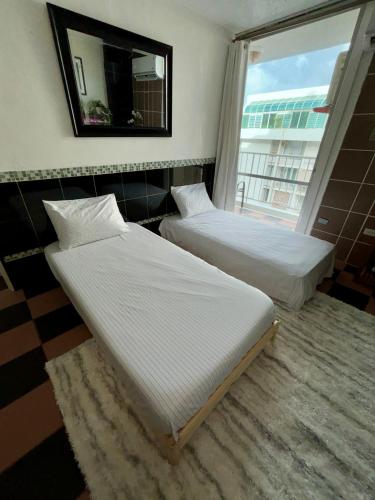two beds in a room with a window at Isla Verde Modern Apartment with Pool in San Juan