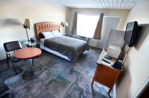 a bedroom with a bed and a table and a television at St. Norbert Hotel in Winnipeg