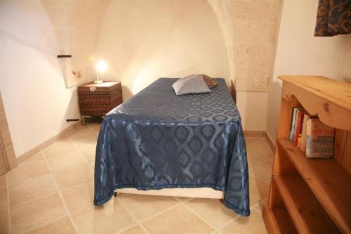 a bedroom with a bed with a blue blanket at Il Casolare Degli Ulivi in Oria