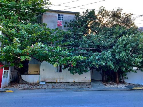 a white building with trees in front of it at Apartment Coral near Mamitas Beach in Playa del Carmen