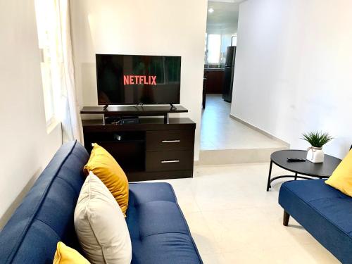 a living room with a blue couch and a tv at Apartment Coral near Mamitas Beach in Playa del Carmen