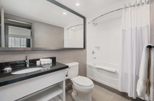 a bathroom with a sink and a toilet and a mirror at Sandman Signature Toronto Airport Hotel in Toronto
