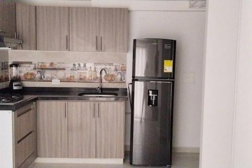 a kitchen with a stainless steel refrigerator and a sink at T3 Apto con Aire y Piscina in Neiva