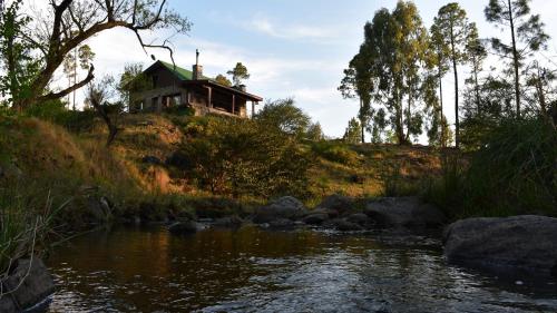 a house sitting on top of a hill next to a river at Cabaña villa alpina Mantillo de bosque in Villa Alpina