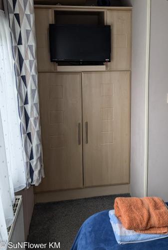 a bedroom with a tv and a bed and a cabinet at Sunflower in Lytchett Minster
