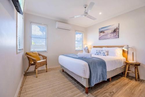 a bedroom with a bed and a chair and windows at Marcoola Sands Retreat Steps from Marcoola Beach in Marcoola