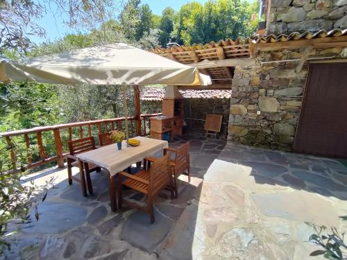 a patio with a table and an umbrella at Casa da Esperança in Lousã