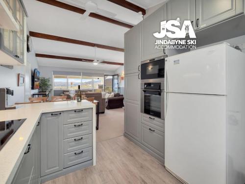 a kitchen with gray cabinets and a white refrigerator at Birralee 1 in Jindabyne