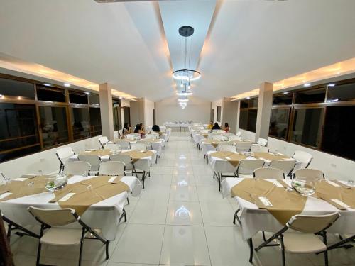 a banquet hall with white tables and white chairs at Hotel Brisas del Rio Guápiles in Jiménez