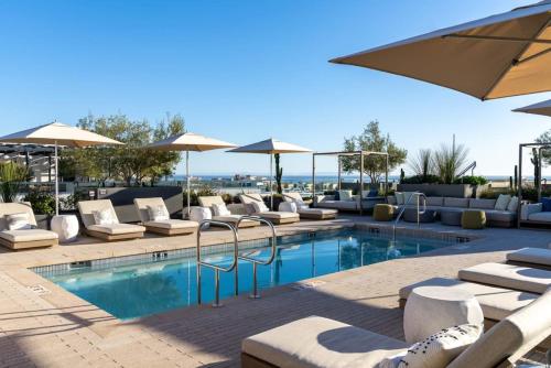 a swimming pool with lounge chairs and umbrellas at The Rose Quartz - Rooftop Pool, Gym Glamorous Santa Monica 2BR in Los Angeles
