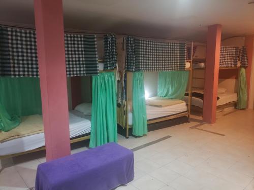 um quarto com 4 beliches com cortinas verdes em Lucky Dorm em Phi Phi Don