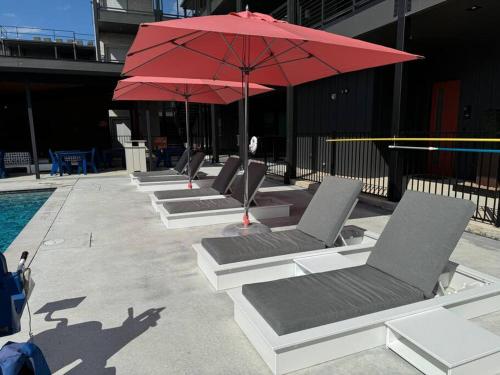 eine Reihe von Stühlen und ein Sonnenschirm neben einem Pool in der Unterkunft Freiheit Loft offers a Lush Couples Getaway near Gruene in New Braunfels