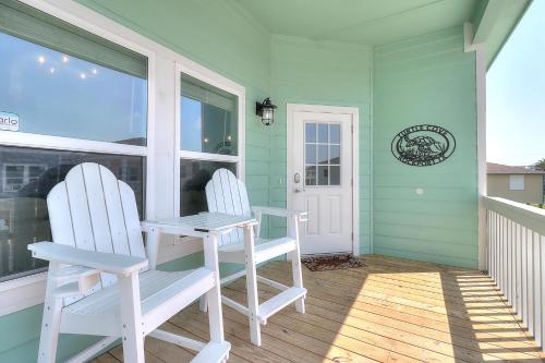 two white chairs sitting on a porch with a table at Turtle Cove in Rockport