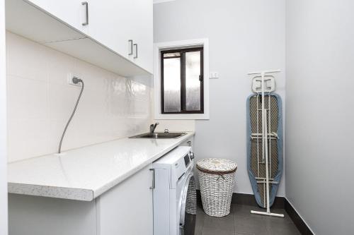 a white kitchen with a sink and a refrigerator at Charmer on Olive in Albury