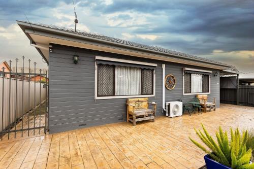 a grey house with a patio and a fence at Charmer on Olive in Albury
