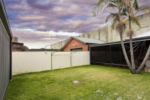 a backyard with a white fence and a palm tree at Charmer on Olive in Albury