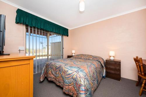 a bedroom with a bed and a tv and a window at Shore Beats Work in Guilderton
