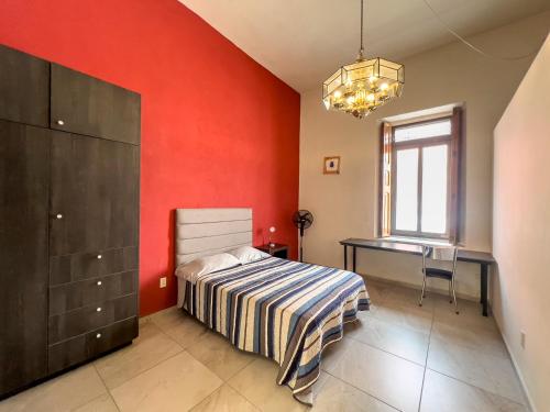 a bedroom with a red wall with a bed and a desk at Casa Morelos StayHouse in San Luis Potosí