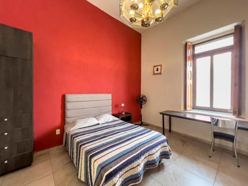 a bedroom with a red wall with a bed and a desk at Casa Morelos StayHouse in San Luis Potosí