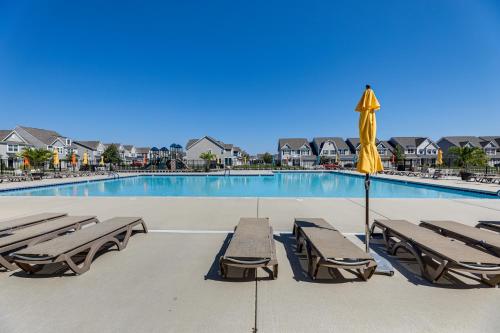 a swimming pool with lounge chairs and an umbrella at 5 Mi to Bethany Beach Resort-Style Gem with Pools! in Ocean View