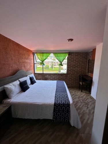 ein Schlafzimmer mit einem großen Bett mit einem großen Fenster in der Unterkunft Marquez-Ote in San Cristóbal de las Casas