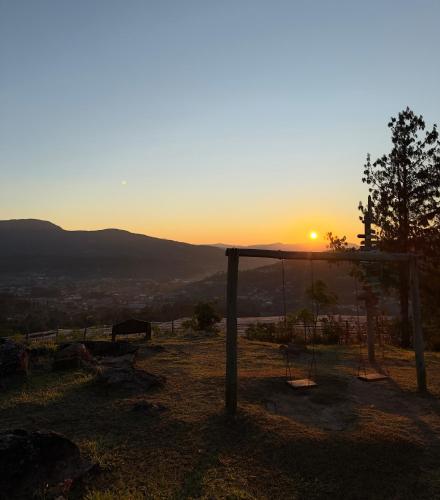 a sunset over a field with a swing at El Pueblito Hotel Boutique in Samaipata