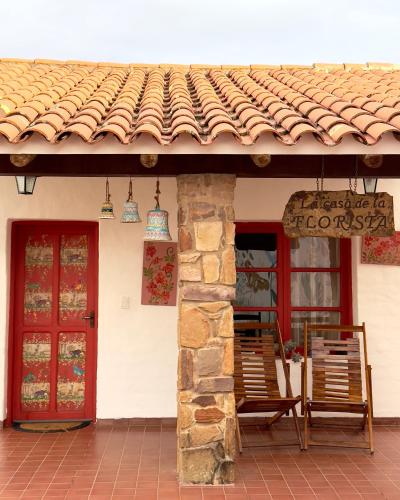a house with two chairs and a red door at El Pueblito Hotel Boutique in Samaipata