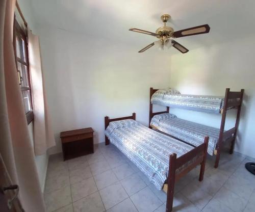 two beds in a room with a ceiling fan at Cabañas Brochero del Valle in Villa Cura Brochero