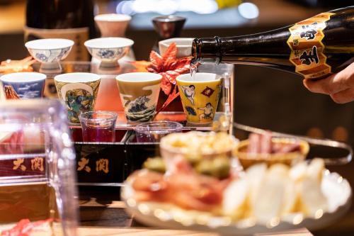 a person pouring a bottle of wine into a plate of food at Hiyori Hotel Osaka Namba Station in Osaka