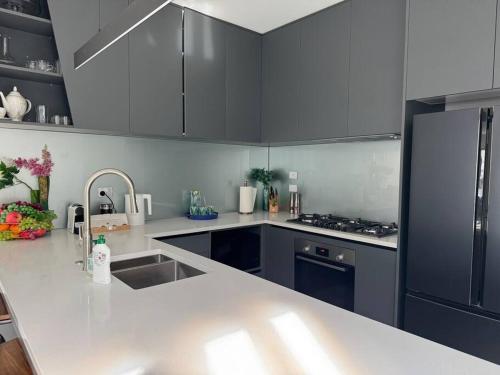 a kitchen with black cabinets and a white counter top at Luxury Villa- Long Bay Manhattan in Auckland