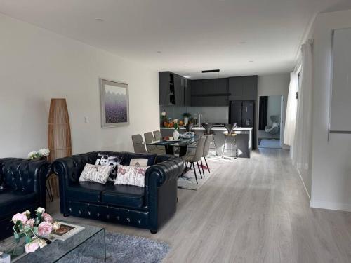 a living room with a couch and a dining room at Luxury Villa- Long Bay Manhattan in Auckland