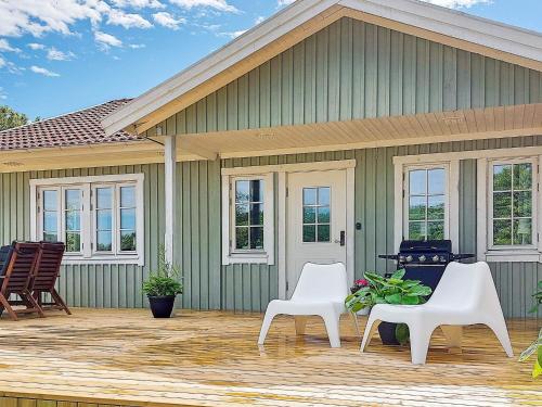 a green house with two white chairs on a deck at 8 person holiday home in ELLÖS in Ellos