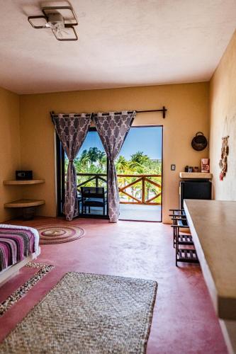 a living room with a door open to a balcony at Atenea 3 private bedrooms in Holbox Island