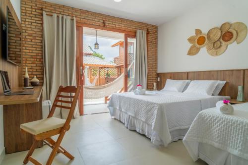 a bedroom with two beds and a chair and a window at Villa do Ze in Jijoca de Jericoacoara
