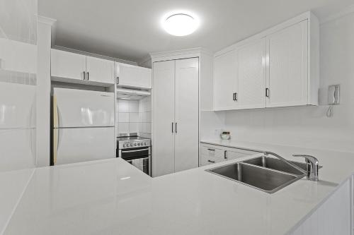 a white kitchen with a sink and a refrigerator at Malibu Apartments in Mooloolaba