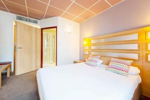 a bedroom with a large white bed with two pillows at Campanile Metz Nord - Talange in Talange