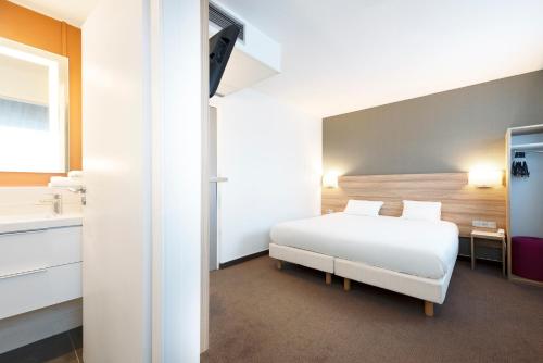 a bedroom with a white bed and a sink at Campanile Metz Nord - Talange in Talange